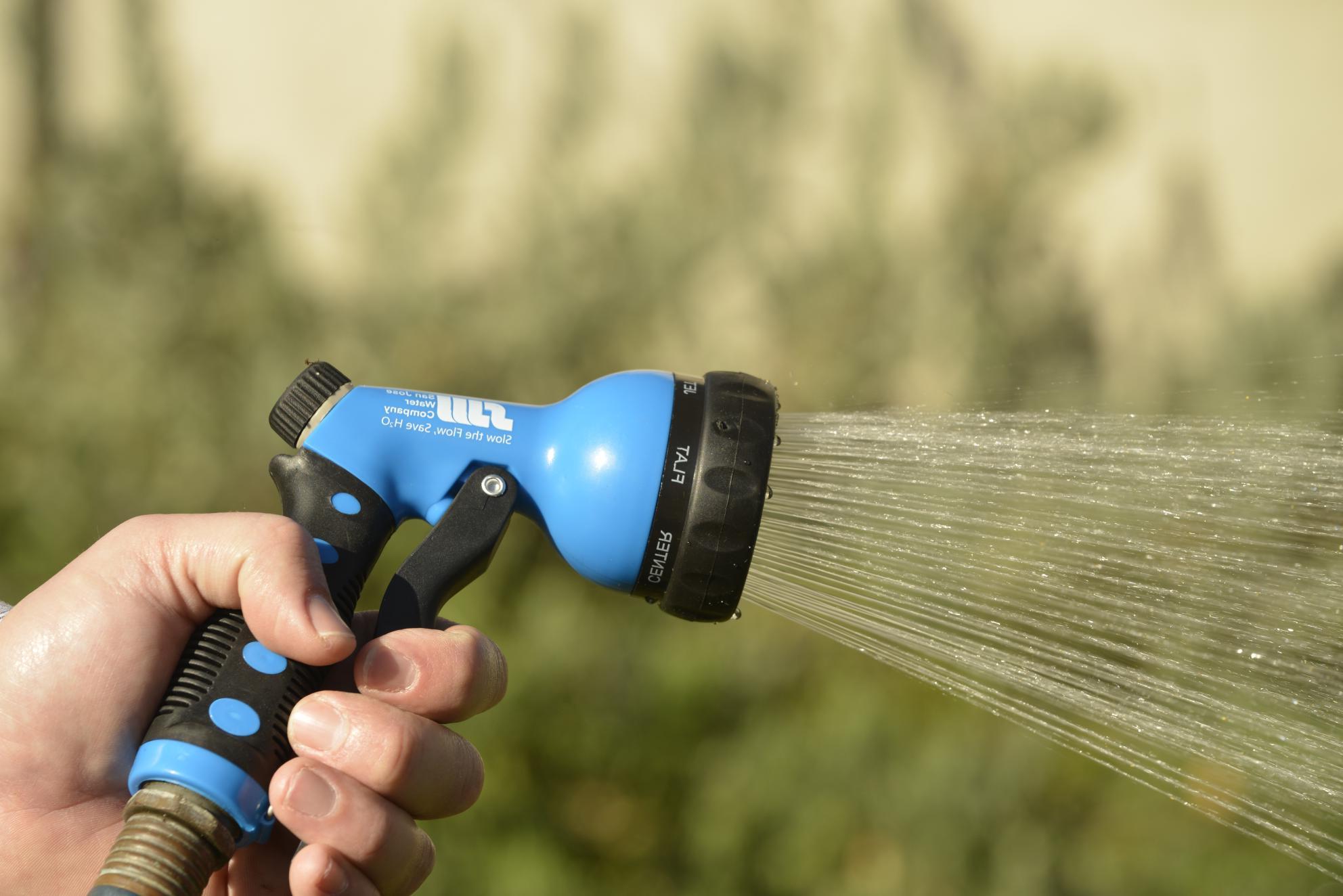 Hand holding San Jose Water-branded garden hose